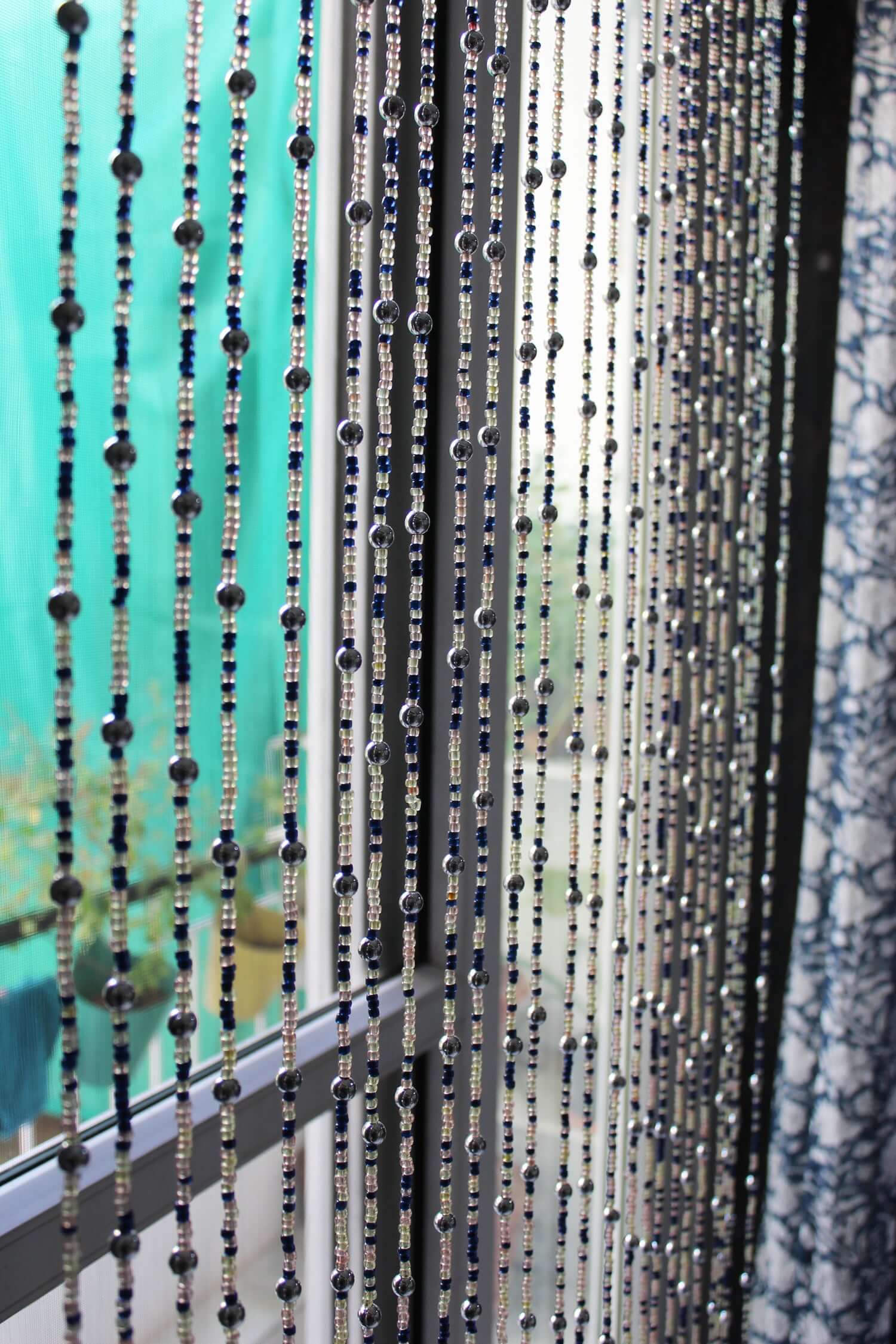 Handmade colorful glass bead strands with jingle bells—perfect for doorways or wall décor. Eco-friendly and crafted by women's artisans in India.